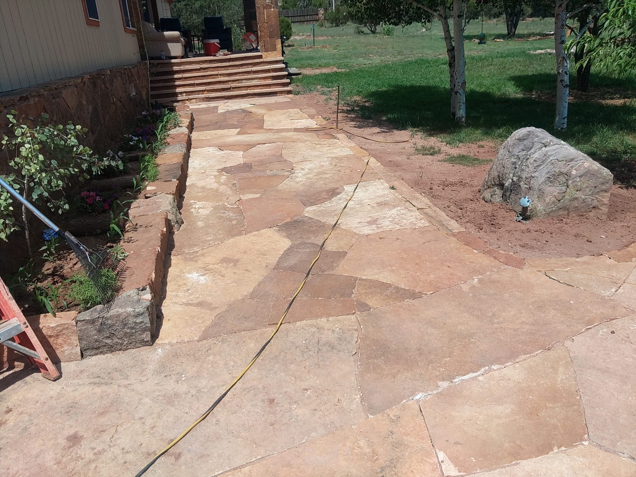 Wide flagstone patio with green lawn and trees